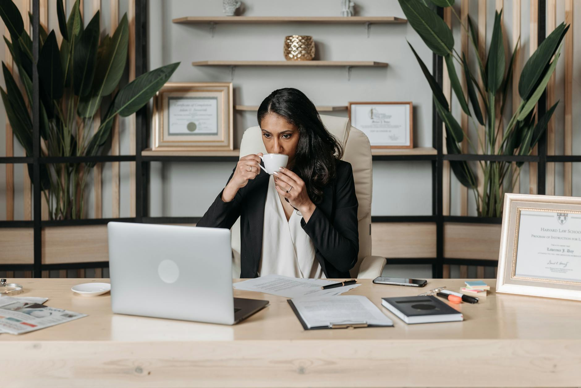 a woman drinking coffee while sitting in the office