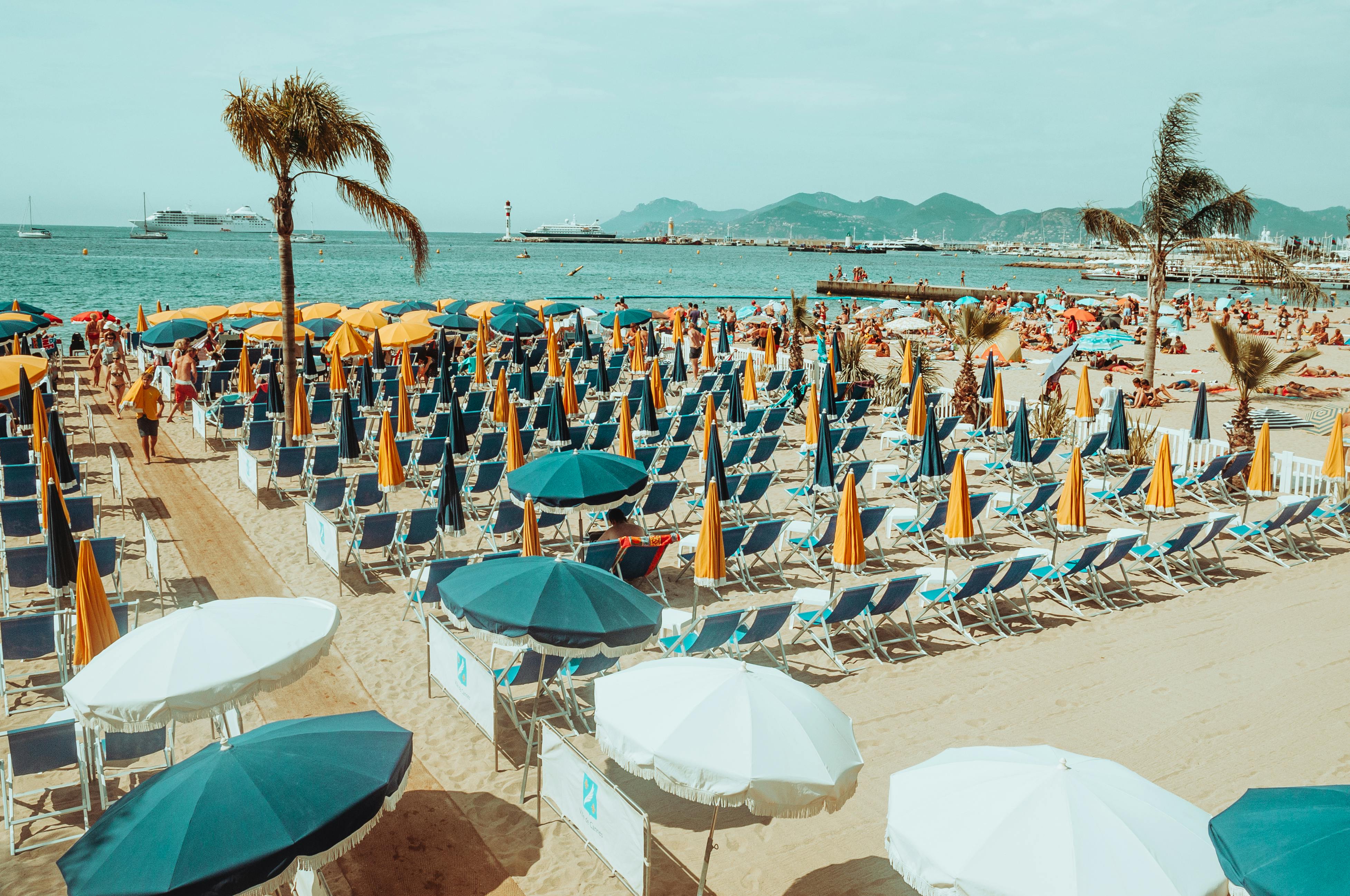 Vibrant beach scene with colorful umbrellas, chairs, and people relaxing by the sea.