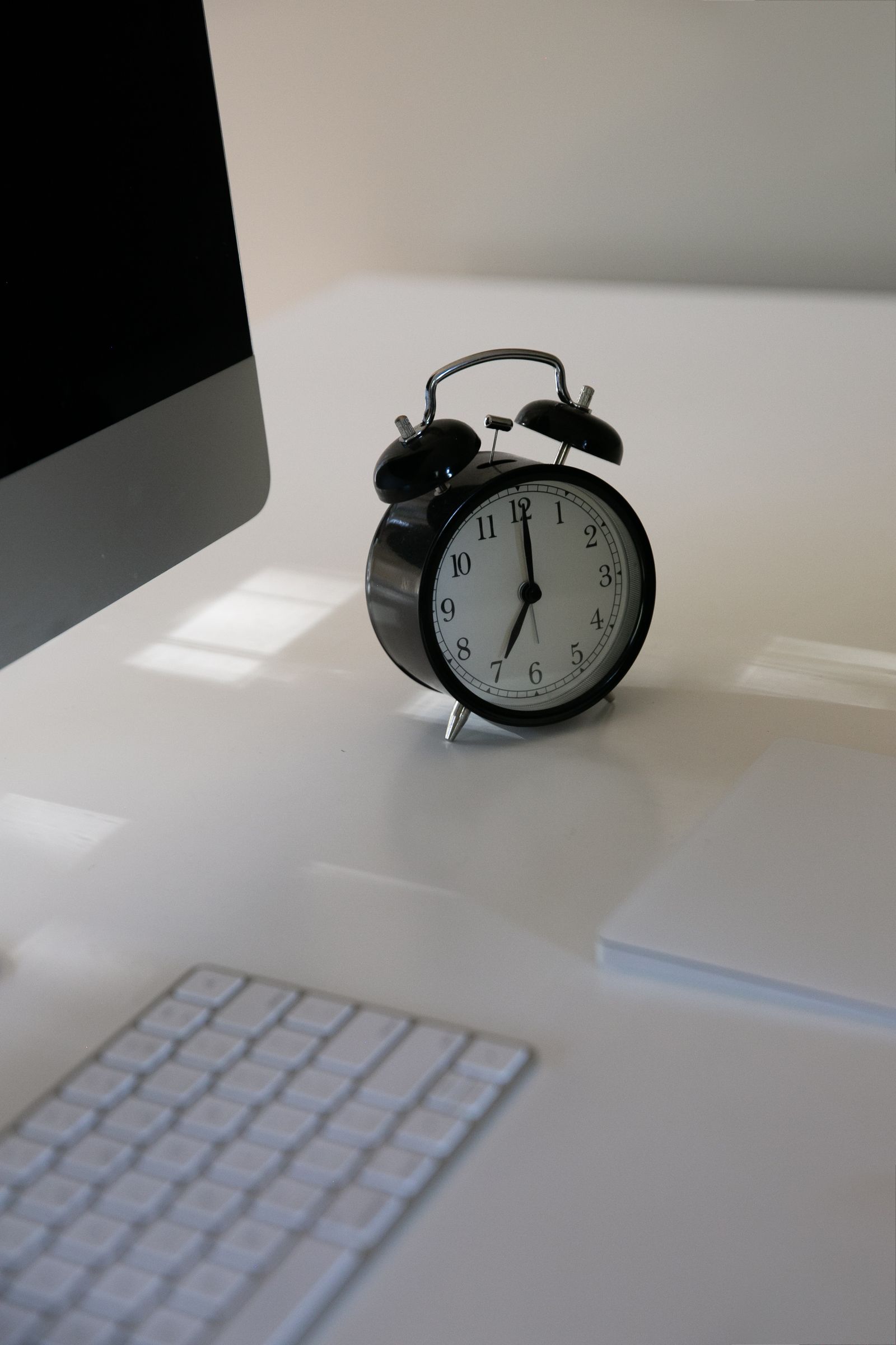 A black alarm clock sitting on a desk