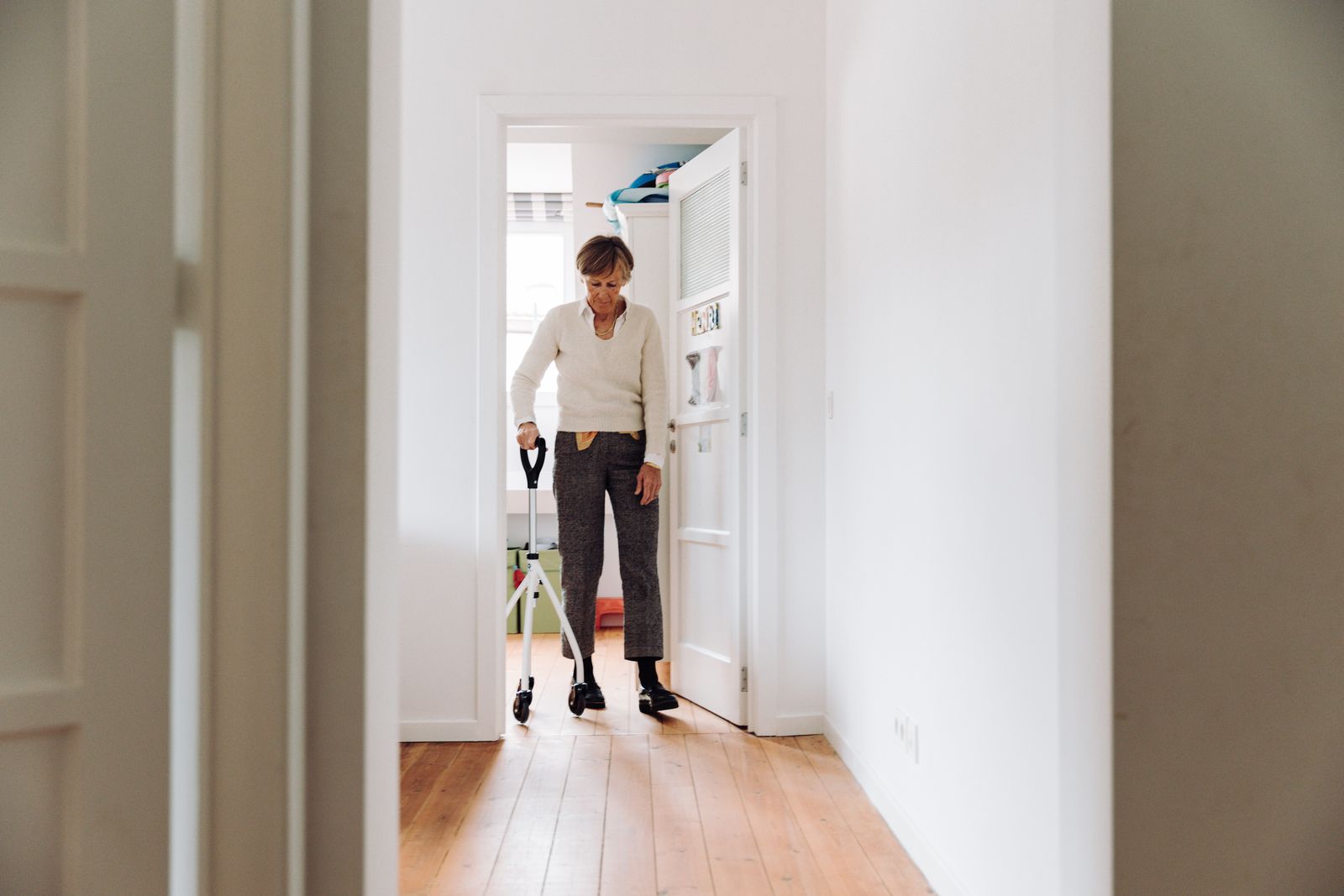 An older woman using a rollator in a bright hallway