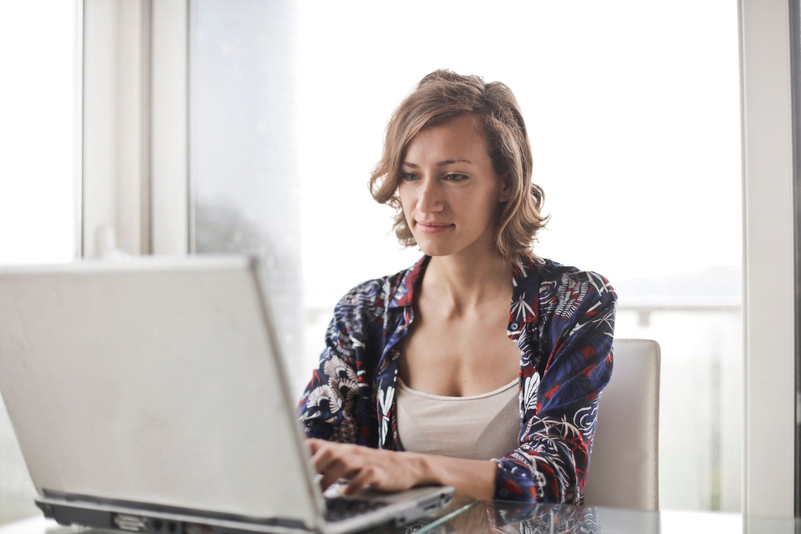 A woman studying at a laptop with notes beside her